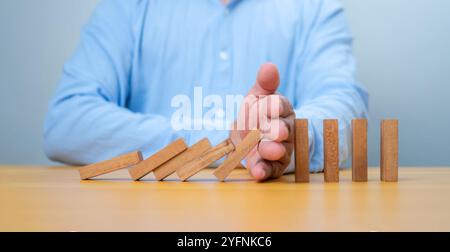 Geschäftsmann Hand stoppt fallende Holzblöcke oder Dominos, Geschäft, Risikomanagement, Lösungen, Versicherungs- und Strategiekonzepte, Risiko und Strategie i Stockfoto