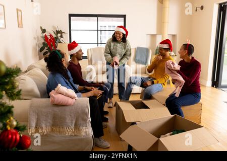weihnachtsmütze tragen, multirassische Freunde, die während weihnachten Geschenke austauschen, zu Hause Stockfoto
