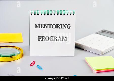 Der Begriff Wirtschaft und Bildung. Konzeptionelles Wort, Phrase, Text des MENTORING-PROGRAMMS es wird in einem Notizbuch auf grauem Hintergrund geschrieben Stockfoto