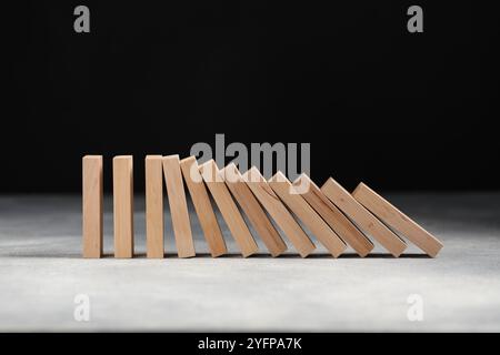 Domino-Effekt. Holzblöcke fallen auf einen grauen Tisch Stockfoto