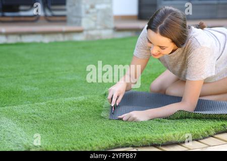 Glückliche Frau, die zu Hause im Garten Kunstrasen installiert Stockfoto