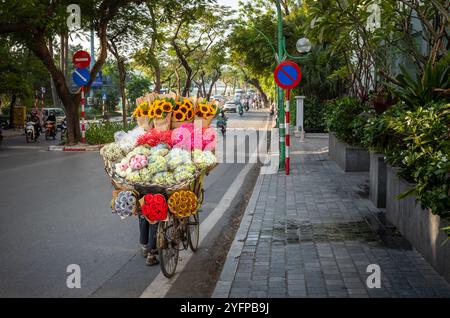 Ein Blumenhändler schiebt ein Fahrrad mit Sträußen aus Lotus (Nelumbo nucifera), Hortensie (Hydrangeaceae), Sonnenblumen (Helianthus) und anderen Blumen Stockfoto