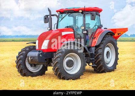 In einem weitläufigen Weizenfeld unter blauem Himmel zeigt ein roter Traktor ein leistungsstarkes, modernes Landmaschinenkonzept Stockfoto