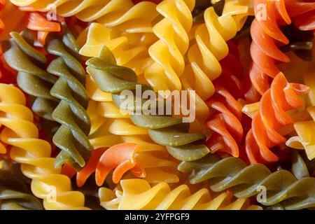 Ungekochte Fusilli Pasta in leuchtenden Farben: Eine faszinierende kulinarische Leinwand aus bunten Spiralen, die einen lebendigen und strukturierten Hintergrund für Gourmet-Kochen schafft. Farbige Trockene Pasta. Rohe Makkaroni Stockfoto