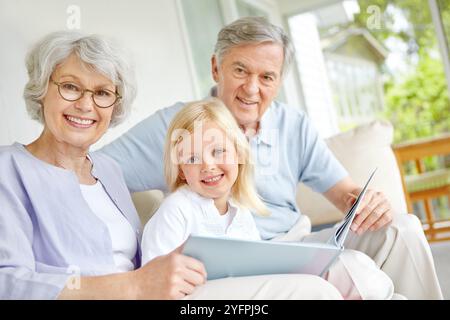 Großeltern, Porträt oder Happy Girl, das Buch zu Hause liest, um zu lernen, sich zu verbinden oder zu wissen. Oma, Großvater und Kind erzählen für Stockfoto