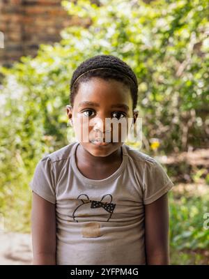 Porträt eines afrikanischen Mädchens mit lockigen Haaren, das hinten im Garten spielt Stockfoto