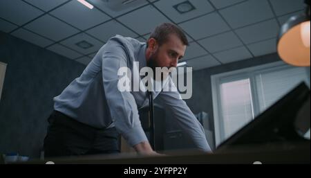 Zeitlupe aggressiver Büroangestellter, die Computermonitore mit der Tastatur zerschlagen, Papiere vom Desktop werfen und schreien. Wütender Geschäftsmann verliert in Wutanfällen die Beherrschung. Finanzieller Verlust oder Entlassung. Stockfoto