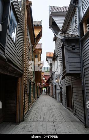 Bergen, Norwegen - 8. August 2022: Enge Gasse zwischen den ikonischen Holzhäusern von Bryggen in Bergen, Norwegen. Historische Gebäude mit ihrem einzigartigen A Stockfoto