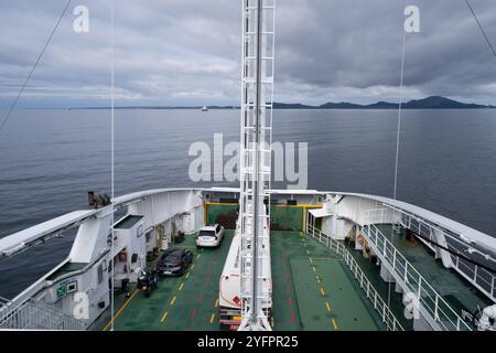 Bergen, Norwegen - 8. August 2022: Ein Blick von der Brücke einer Fähre, die durch einen ruhigen norwegischen Fjord fährt. Fahrzeuge werden auf dem Deck unter einem geparkt Stockfoto