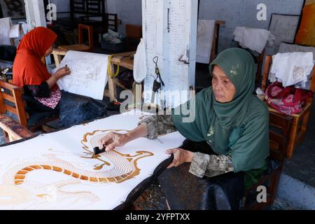 Batikproduktion. Frau, die heißes Wachs benutzt, um ein Drachendesign zu skizzieren. Yogyakarta. Indonesien. Stockfoto