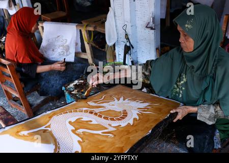 Batikproduktion. Frau, die heißes Wachs benutzt, um ein Drachendesign zu skizzieren. Yogyakarta. Indonesien. Stockfoto