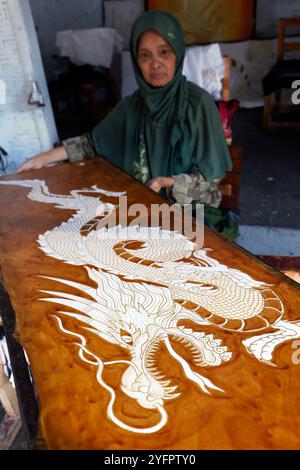 Batikproduktion. Frau, die heißes Wachs benutzt, um ein Drachendesign zu skizzieren. Yogyakarta. Indonesien. Stockfoto