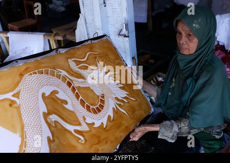 Batikproduktion. Frau, die heißes Wachs benutzt, um ein Drachendesign zu skizzieren. Yogyakarta. Indonesien. Stockfoto