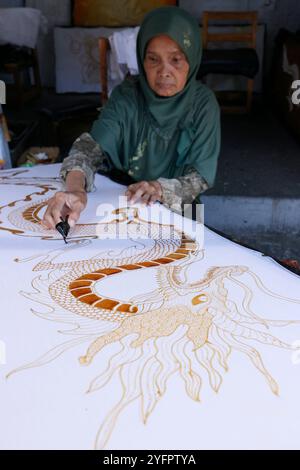 Batikproduktion. Frau, die heißes Wachs benutzt, um ein Drachendesign zu skizzieren. Yogyakarta. Indonesien. Stockfoto