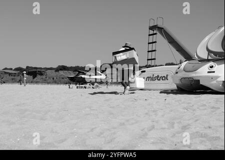 Monochrom eines Bola de berlim-Verkäufers, der sich auf dem Weg über einen Sandstrand macht Stockfoto