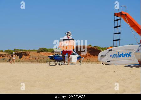 Der Verkäufer von Bola de berlim macht sich auf den Weg über einen Sandstrand in der Algarve Stockfoto