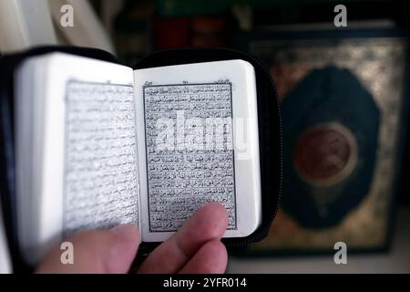 Ein muslimischer Mann liest einen kleinen heiligen Koran auf arabisch. Nahaufnahme der Hand. Stockfoto