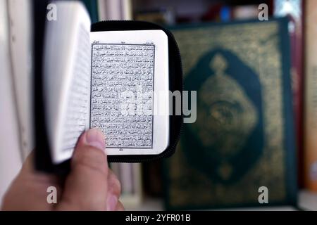 Ein muslimischer Mann liest einen kleinen heiligen Koran auf arabisch. Nahaufnahme der Hand. Stockfoto