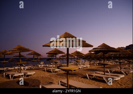 Palapasreihen und leere Liegen während sich die Dämmerung über der Küste der Algarve niederschlägt Stockfoto