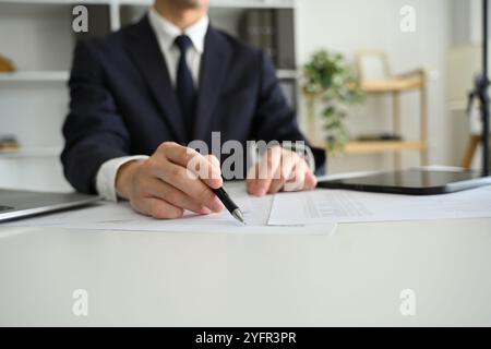 Professioneller Geschäftsmann, der Vertragsdokumente am Schreibtisch überprüft Stockfoto