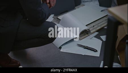 Büroraub oder Mordfall: Kriminalermittlungsteam arbeitet. Ein männlicher Detective untersucht Beweise am Tatort. Kriminalistin und Polizistin sucht im Hintergrund nach Fingerabdrücken. Stockfoto