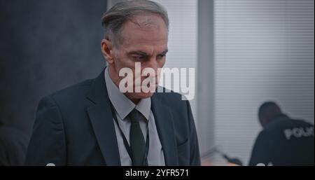 Büroraub oder Mordfall: Kriminalermittlungsteam arbeitet. Ein männlicher Detective untersucht Beweise am Tatort. Kriminalistin und Polizistin sucht im Hintergrund nach Fingerabdrücken. Stockfoto