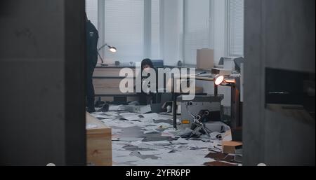 Diverse Ermittlungsmitarbeiter arbeiten am Tatort: Weibliche Forensikologin fotografiert Beweise mit Kamera, afroamerikanische Polizistin sucht nach Fingerabdrücken. Banküberfall oder Mordfall. Stockfoto