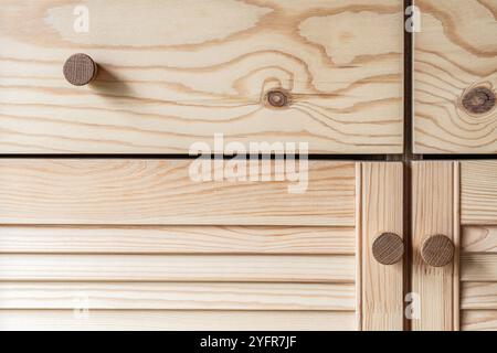 Holztüren mit Lamellen und Holzgriff in Nahaufnahme. Die Türen der Außenküche sind aus hellem Kiefernholz mit natürlichem Masermuster gefertigt Stockfoto