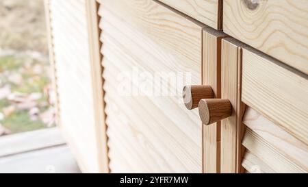 Holztüren mit Lamellen und Holzgriff in Nahaufnahme. Die Türen der Außenküche sind aus hellem Kiefernholz mit natürlichem Masermuster gefertigt Stockfoto