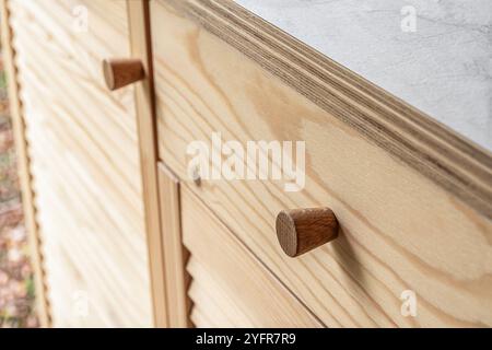 Holztüren mit Lamellen und Holzgriff in Nahaufnahme. Die Türen der Außenküche sind aus hellem Kiefernholz mit natürlichem Masermuster gefertigt Stockfoto