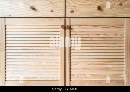 Holztüren mit Lamellen und Holzgriff in Nahaufnahme. Die Türen der Außenküche sind aus hellem Kiefernholz mit natürlichem Masermuster gefertigt Stockfoto