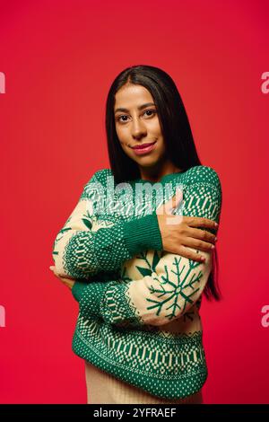 Mit einem warmen Lächeln umschließt eine junge Frau ihre Pullover mit gemütlichem Design in auffälligen Farben. Stockfoto