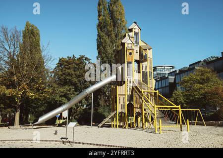 Moderner Kinderspielplatz für Spiele im Freien, ein Rutschrohr aus Metall, Pyramiden aus Holz, Gummibeschichtung auf dem Spielplatz. Kinderspielgr Stockfoto