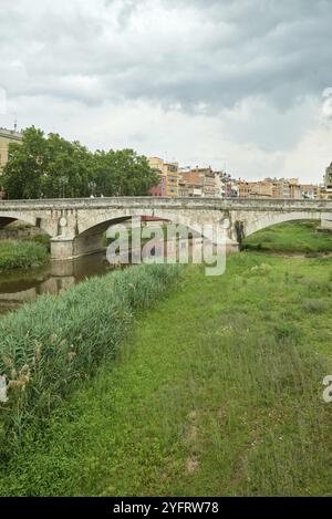 Farbenfrohe gelbe und orangefarbene Häuser und Brücke Pont de Sant Agusti spiegelten sich im Fluss Onyar in Girona, Katalonien, Spanien, wider. Kirche von Sant Feliu und Stockfoto