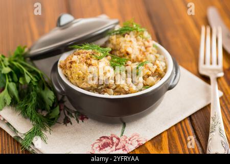 Gekochtes Buchweizen mit Hühnerfleischbällchen in Keramikschale auf Holztisch. Stockfoto