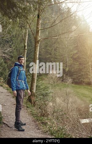 Ein Tourist mit Rucksack steht auf einem Bergweg und schaut in die Ferne. Das Konzept von Reisen und Abenteuer. Traveler man mit Rucksack Stockfoto