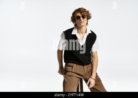 Ein hübscher junger Mann zeigt sein welliges Haar und sein herbstliches Outfit und strahlt Charme in einem Studio aus. Stockfoto