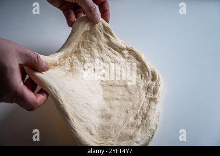 Die Hände des Pizzamakers oder Küchenchefs machen einen Kreis aus Teig für die Pizzabasis. Der Prozess der Pizza. Hochwertige Fotos Stockfoto