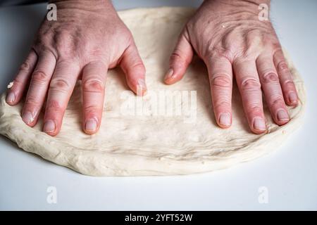 Die Hände des Pizzamakers oder Küchenchefs machen einen Kreis aus Teig für die Pizzabasis. Der Prozess der Pizza. Hochwertige Fotos Stockfoto