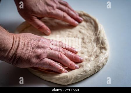 Die Hände des Pizzamakers oder Küchenchefs machen einen Kreis aus Teig für die Pizzabasis. Der Prozess der Pizza. Hochwertige Fotos Stockfoto