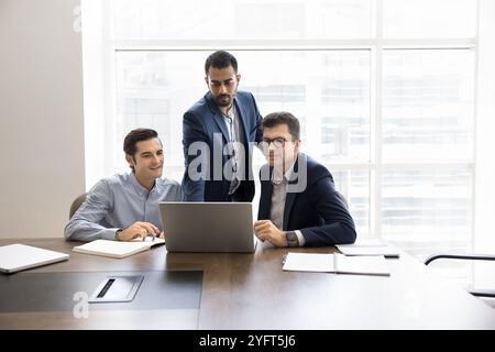 Multiethnisches männliches Geschäftsteam von drei Unternehmern, die am Laptop sprechen Stockfoto