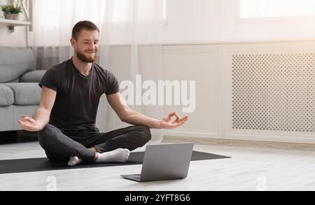 Millennial Kerl meditieren mit Trainer online über Laptop Stockfoto