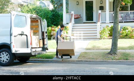 Männlicher Fahrer, Der Den Wagen Benutzt, Um Das Paket Vom Van Zum Haus Zu Liefern Stockfoto