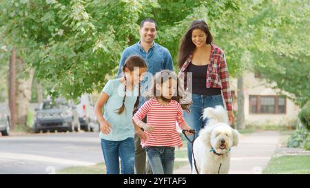 Smiling Family Outdoor Walking Dog Entlang Der Vorstadt Street Stockfoto