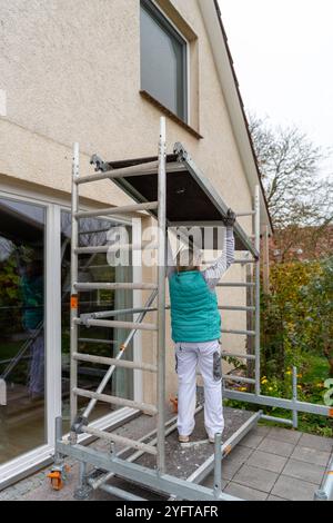 Gerüstbauerin, Malerin baut ein mobiles Gerüst am Einfamilienhaus auf, Modell freigegeben für redaktionelle Nutzung, Gerüstbauer *** Gerüstbauer, Maler errichtet mobiles Gerüst auf einem Einfamilienhaus, Modell freigegeben für redaktionelle Nutzung, Gerüsthalter 20241105-DSC 8677 Stockfoto