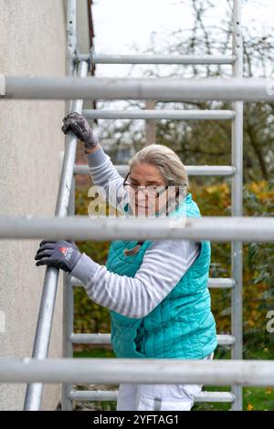 Gerüstbauerin, Malerin baut ein mobiles Gerüst am Einfamilienhaus auf, Modell freigegeben für redaktionelle Nutzung, Gerüstbauer *** Gerüstbauer, Maler errichtet mobiles Gerüst auf einem Einfamilienhaus, Modell freigegeben für redaktionelle Nutzung, Gerüsthalter 20241105-DSC 8670 Stockfoto