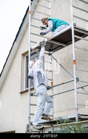 Gerüstbauerin, Malerin und Maler bauen ein mobiles Gerüst am Einfamilienhaus auf, Modell freigegeben für redaktionelle Nutzung, Gerüstbauer *** Gerüstbauer, Maler und Maler, die ein mobiles Gerüst auf einem Einfamilienhaus aufstellen, Modell freigegeben für redaktionelle Nutzung, Gerüstbauer 20241105-DSC 8715 Stockfoto