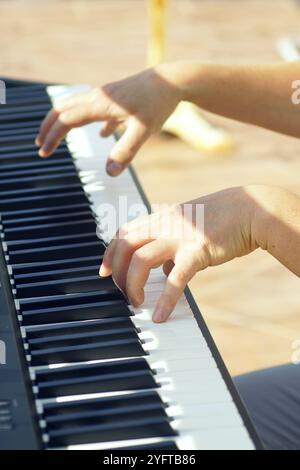 Musiker, der die Tasten des E-Pianos berührt. Konzert im Freien: Pianist spielt Melodie, Nahaufnahme. Musikwiedergabe. Stockfoto