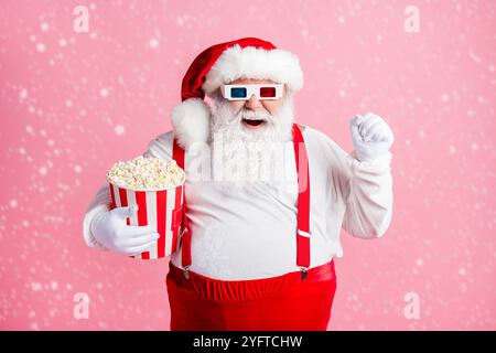 Porträt seiner er schön attraktiv fröhlich fröhlich froh bärtig Fat Santa beobachten Comedy Film Essen Mais Spaß Zeitvertreib Amusement isoliert rosa Stockfoto