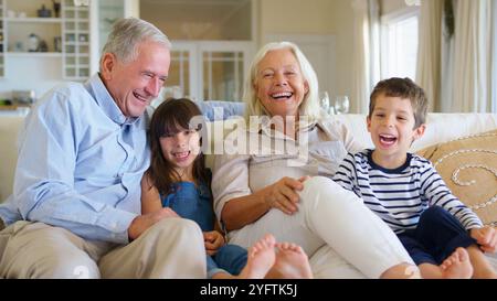 Porträt Lächelnder Großeltern, Die Mit Enkelkindern Zu Hause Auf Dem Sofa Sitzen Stockfoto
